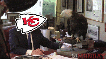 a man sitting at a desk with a statue of an eagle and a kc logo on his head