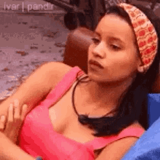 a woman in a pink tank top and headband is sitting in a chair .