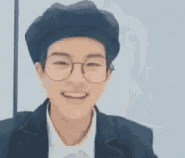 a young man wearing glasses and a beret is smiling