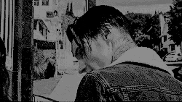a man in a denim jacket is looking down at something