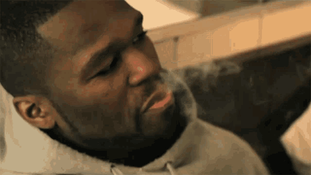 a man with a beard is smoking a cigarette with smoke coming out of his mouth