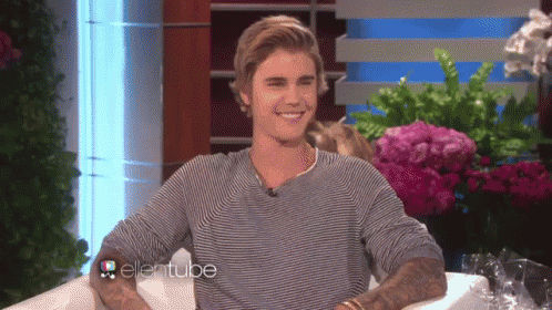 justin bieber is smiling while sitting in a chair with the ellentube logo behind him
