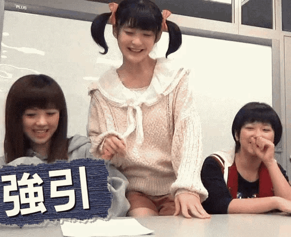 three girls are sitting at a table with a sign that says " plus "