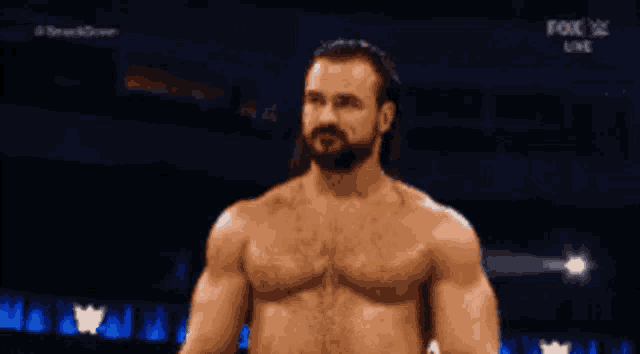 a shirtless wrestler is standing in front of a fox live advertisement