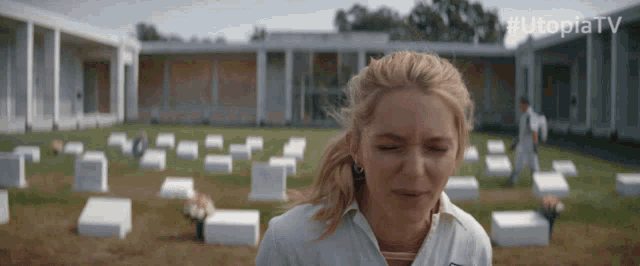 a woman stands in front of a cemetery with the hashtag utopiatv at the bottom