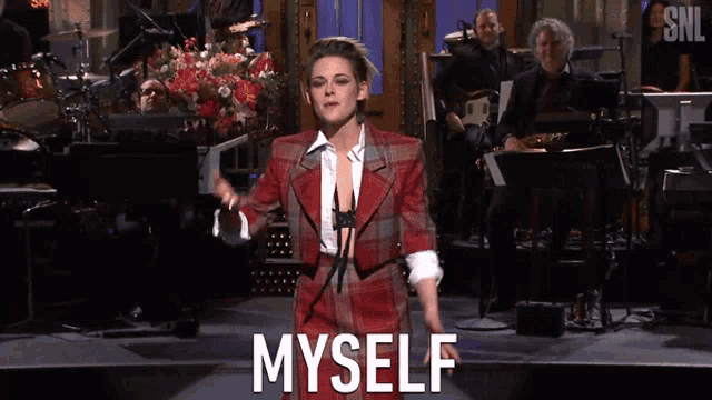 a woman in a plaid suit stands on a stage with the words myself written on it