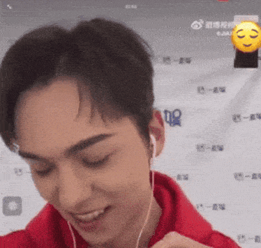 a man wearing headphones and a red hoodie is smiling and looking at the camera .