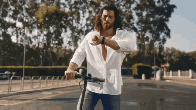 a man in a white shirt is riding an electric scooter and looking at his watch .