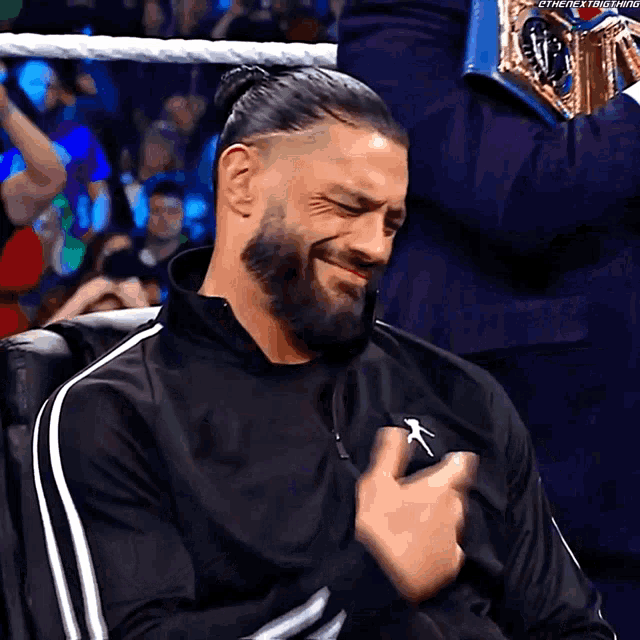 a man with a beard is sitting in a chair with his hands on his chest ..