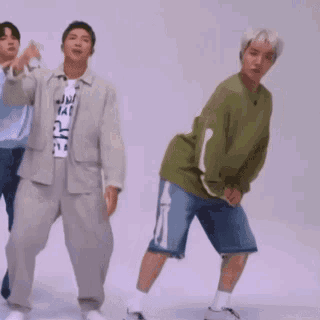 a group of men are dancing together in front of a white wall .