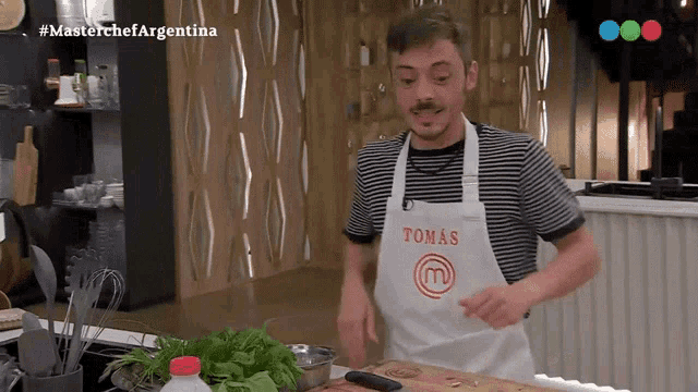 a man wearing a white apron that says tomas on it