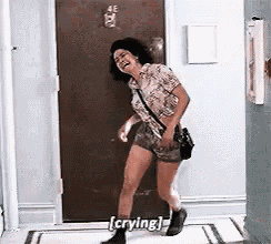 a woman is standing in a hallway and crying while laughing .