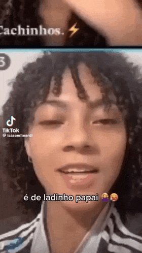 a woman with curly hair is talking on a video call with a lightning bolt in the background .