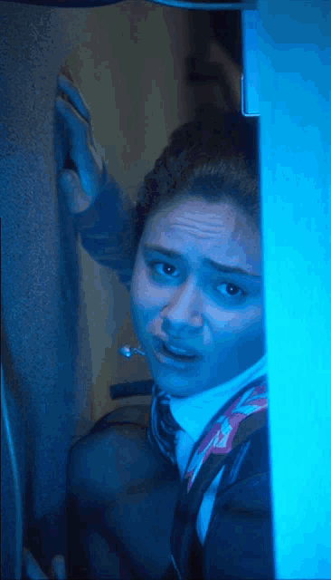 a woman with a scarf around her neck looks scared in a dark room