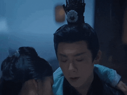 a man and a woman are looking at each other and the woman has a flower in her hair