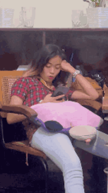 a woman sits in a chair looking at her cell phone