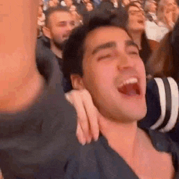 a man is screaming in a crowd of people at a sports game .