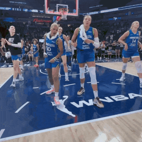 a group of female basketball players wearing minnesota uniforms are dancing on the court