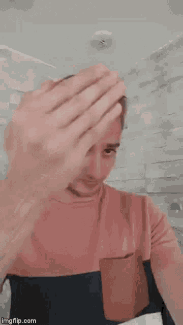 a man in a pink shirt is making a funny face while holding his fist in the air .
