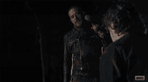 a man in a leather jacket is holding a hammer in his hand in the dark .