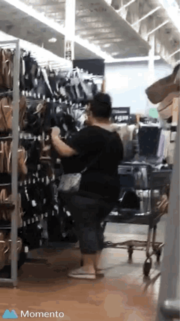 a woman in a black shirt is looking at shoes in a store with the words momento on the bottom