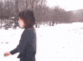 a woman in a black jacket is walking in the snow .