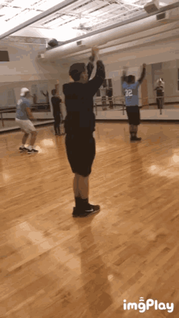 a man in a blue shirt with the number 32 on it stands in a gym