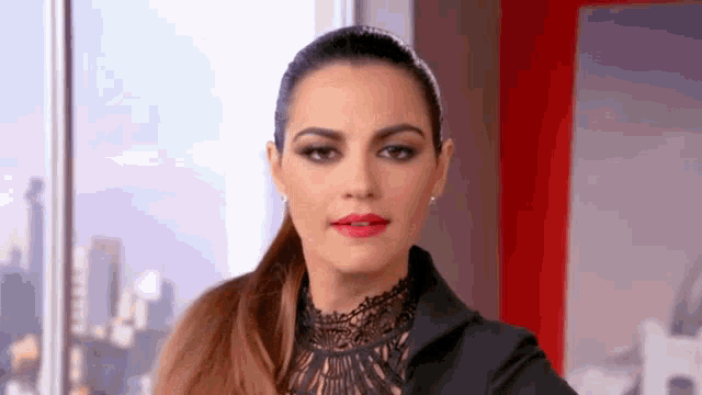 a woman is wearing a black jacket and red lipstick .