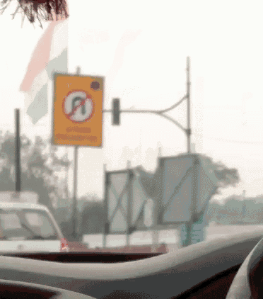 a no parking sign is in the foreground of a blurry picture