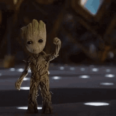 groot from guardians of the galaxy is flexing his muscles while standing on a table .