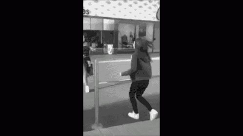 a black and white photo of two women standing next to each other on the sidewalk .