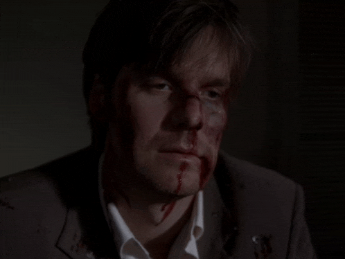 a man with blood on his face is wearing a brown suit