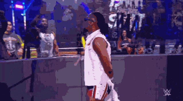 a man in a white nike shirt stands in front of a crowd at a wrestling event