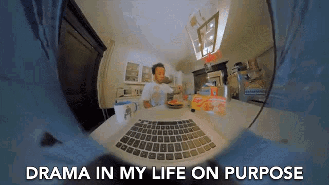 a man sitting at a table with a laptop and the words " drama in my life on purpose " below him