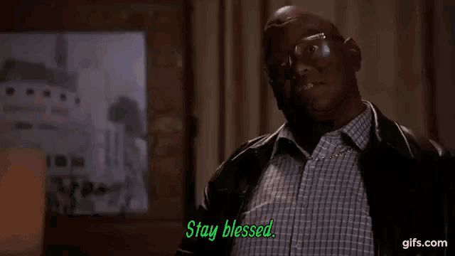 a man wearing glasses and a plaid shirt is saying `` stay blessed '' in a room .