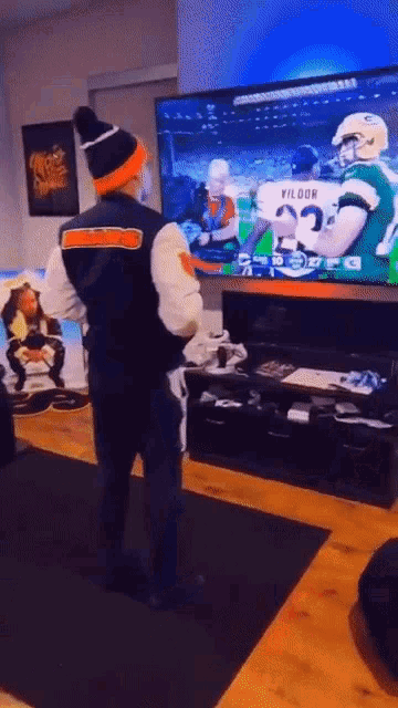 a man standing in front of a television with a vildor jersey