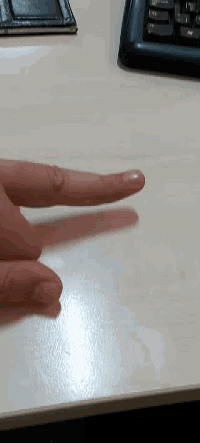 a person 's hand is making a peace sign on a desk