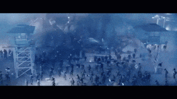 a crowd of people are walking in a dark area with a tower in the background