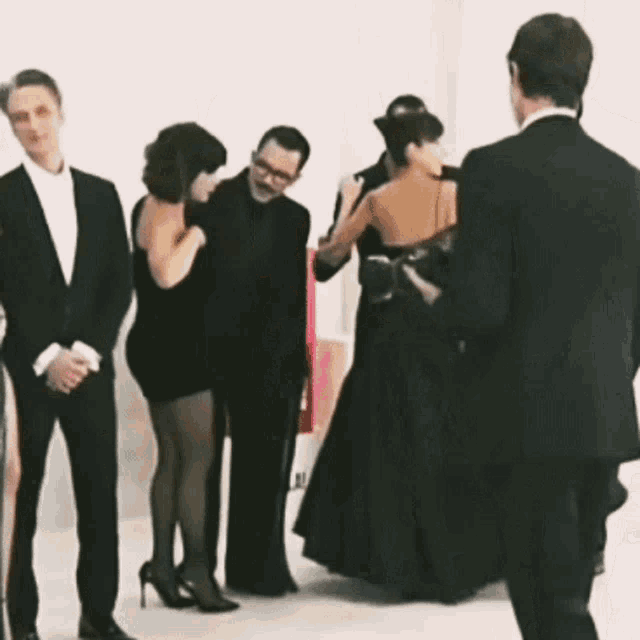 a woman in a black dress is standing in a line with other people