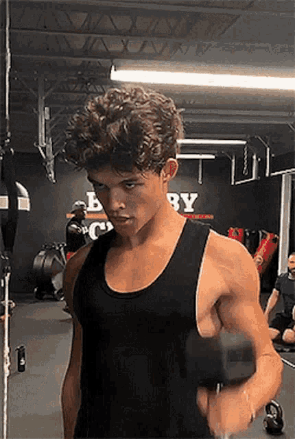 a young man in a black tank top is working out in a gym .