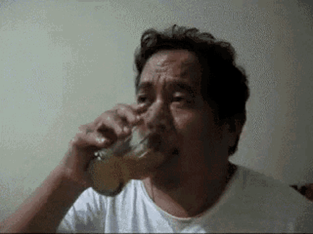 a man in a white shirt is drinking a glass of beer