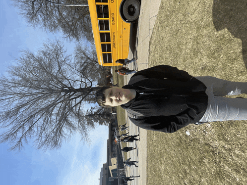 a boy stands in front of a yellow school bus that says " board "
