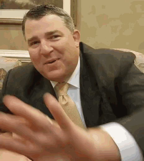 a man in a suit and tie is waving