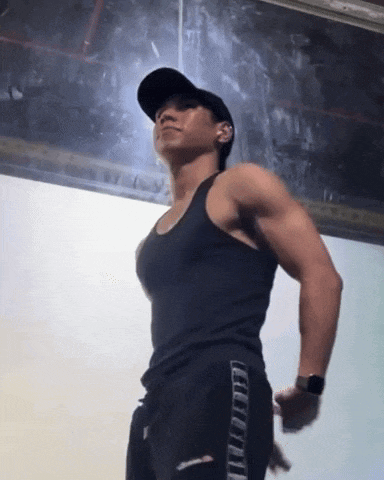 a man wearing a black tank top and black pants is standing in a dark room