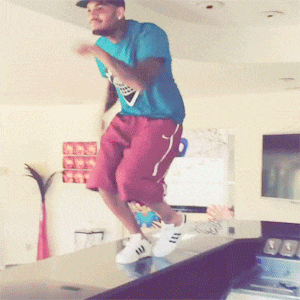 a man in a blue shirt is jumping over a table
