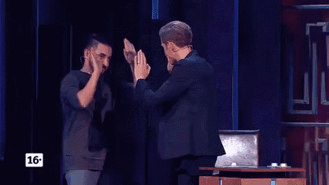 a man in a black shirt is dancing on a stage with a sign that says 16 on it .