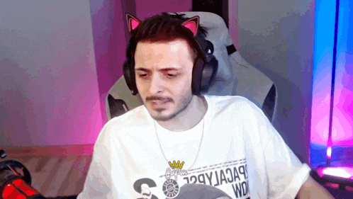 a man wearing headphones and a cat ear headband is sitting in a chair ..