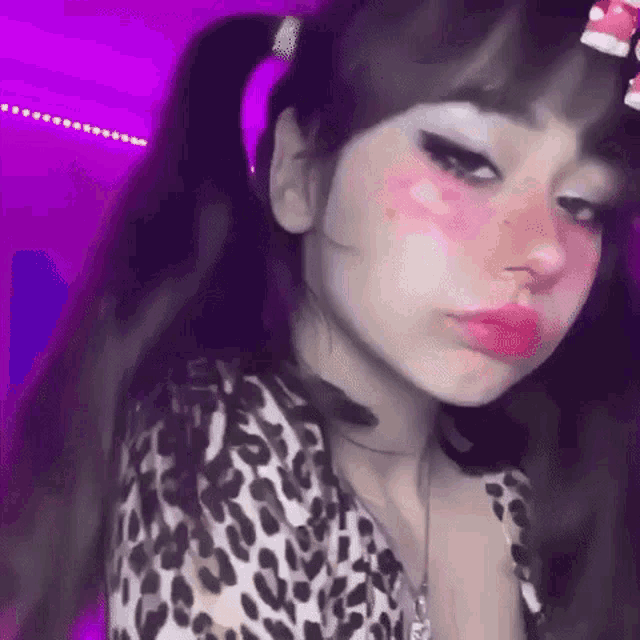 a girl with pigtails is wearing a leopard print shirt and making a face .
