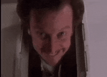 a man in a suit and tie is smiling while looking out of a hole in the wall .