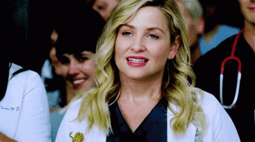 a woman in a white lab coat is smiling in front of a crowd of people .